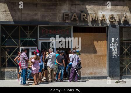 Lots of people waiting in front of a dilapidated and half boarded up pharmacy, Havana Centro district, Havana, Cuba Stock Photo