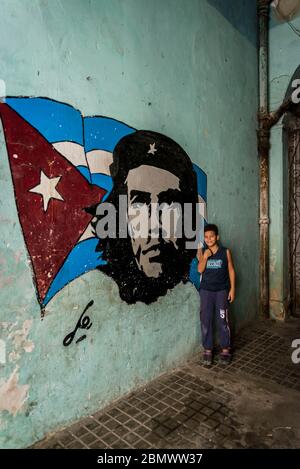 Boy next to Che Guevara wall painting , Old City Centre, Havana Vieja, Havana, Cuba Stock Photo