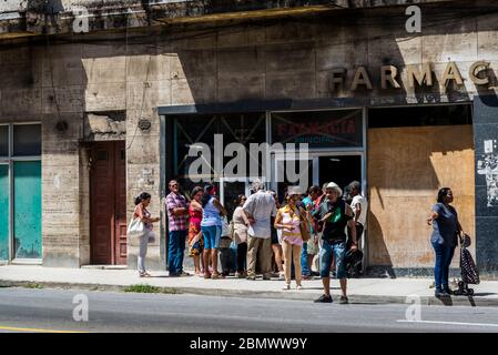 Lots of people waiting in front of a dilapidated and half boarded up pharmacy, Havana Centro district, Havana, Cuba Stock Photo