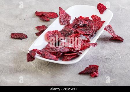 Diet healthy eating concept. Dried beet chips or baked beets in a white rectangular plate, on a gray concrete background. Organic natural food. Copy s Stock Photo