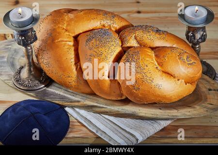 Shabbat challah on a wooden stand, with candles and a rustic bale. Shabbat Shalom Stock Photo