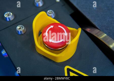 Red emergency button with arrows on black panel Stock Photo