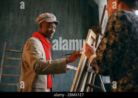 Portrait painter at the easel draws female model Stock Photo
