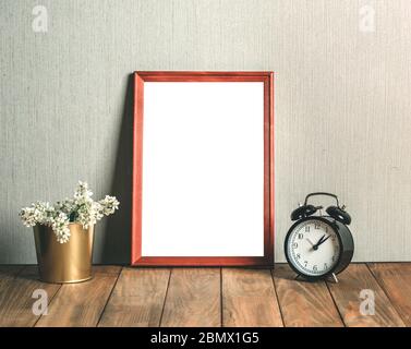Wooden frame on the table with a bunch of white flowers and a clock Stock Photo