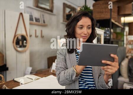Smiling Asian woman working on a tablet in her store Stock Photo