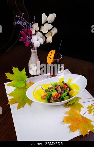 Salad with liver, arugula, orange, spinach and almonds on plate over dark stone surface. Stock Photo