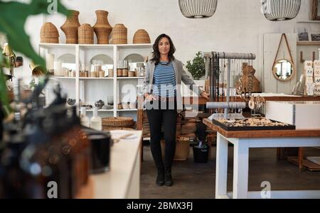 Smiling young Asian woman standing in her stylish store Stock Photo