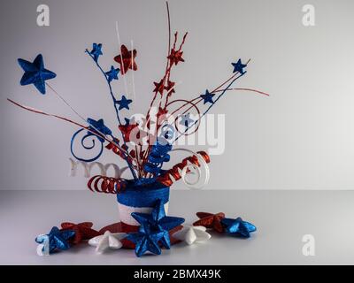 Red, white and blue top hat with stars and ribbons on top and glitter stars lined up along it on a white background for Memorial Day, 4th of July, Vet Stock Photo