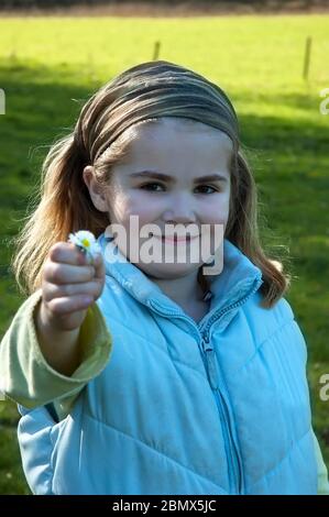 an adorable young child offers a flower Stock Photo