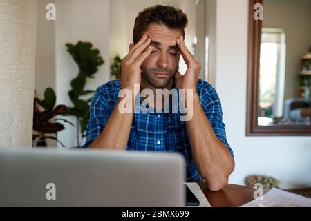 Man looking stressed while working remotely from home Stock Photo