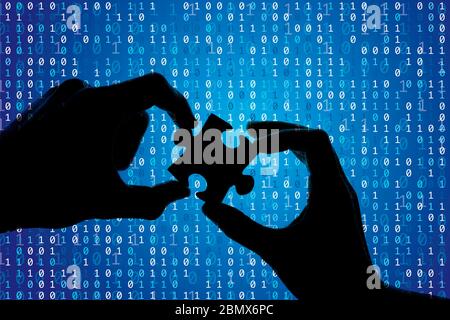 Silhouette of a hands holding a jigsaw puzzle piece with binary background Stock Photo