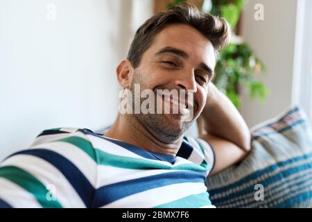 Smiling young man relaxing on his living room sofa Stock Photo