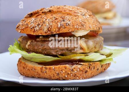 Freshly cooked home-made burger with meat, salad, onions, cucumbers, tomatoes and ketchup Stock Photo