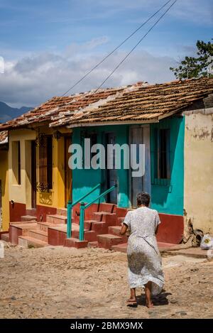 Woman walking in Typical cobblestoned street with colourful houses in the old colonial centre of the town, Trinidad, Cuba Stock Photo