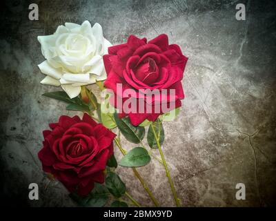 Artificial flowers: three roses on a dark background Stock Photo