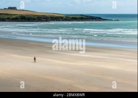 Inchydoney, West Cork, Ireland. 11th May, 2020. A woman walks alone on the beach at Inchydoney in West Cork on a day of sunshine and high winds. Credit: AG News/Alamy Live News Stock Photo