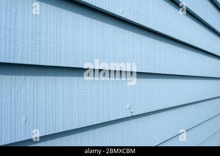 Blue painted wooden clapboard planks on the side of a building , close up. Stock Photo