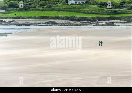 Inchydoney, West Cork, Ireland. 11th May, 2020. A couple walk on the beach at Inchydoney in West Cork on a day of sunshine and high winds. Credit: AG News/Alamy Live News Stock Photo