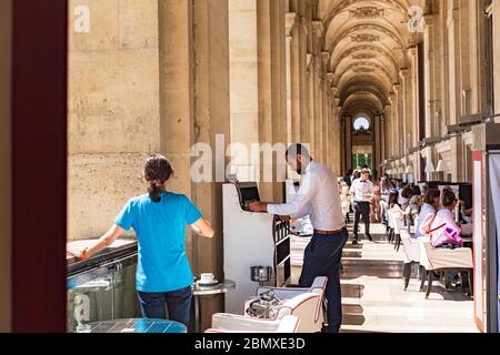 Parisians and tourists enjoy summer day drinks in cafe on a terrace of Louvre Stock Photo