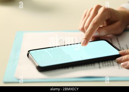 Executive woman hand signing digital contract on lighted smart phone screen with finger on a desk in the office Stock Photo