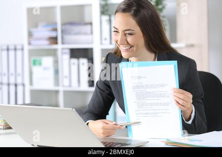 Happy executive woman pointing contract signature space on videocall on laptop sitting on her desk at office Stock Photo