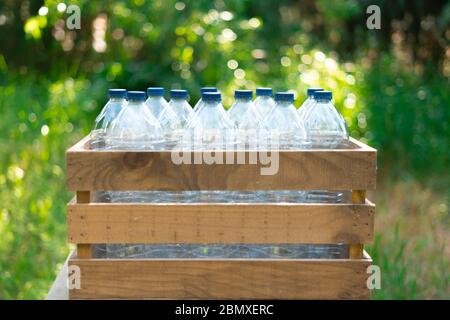 Reuse of the concept of recycling plastic bottles. Plastic bottles with stoppers in a recycled wooden box with beautiful sunset in the garden Stock Photo