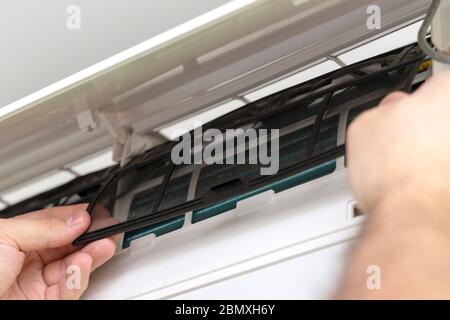 Male technician repairing and reading air conditioners. Opening the cover and cleaning the right filter Stock Photo