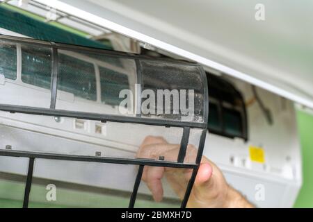 Male technician repairing and reading air conditioners. Cover opening and close-up of one filter Stock Photo