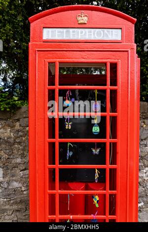 K6 red telephone box in a quiet area of Bristol UK with no glass but decorated with colourful ceramic baubles Stock Photo