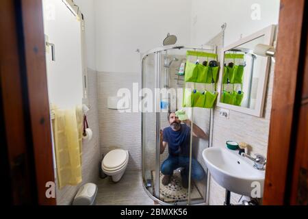 man cleaning the bathtub glass during coronavirus quarantine Stock Photo