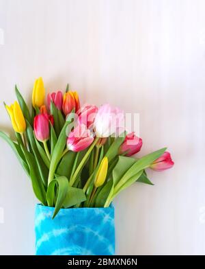 Multi-colored tulips in a woven bag on a white blurred background Stock Photo