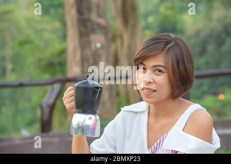 The coffee pot in the hands of Asian women. Stock Photo