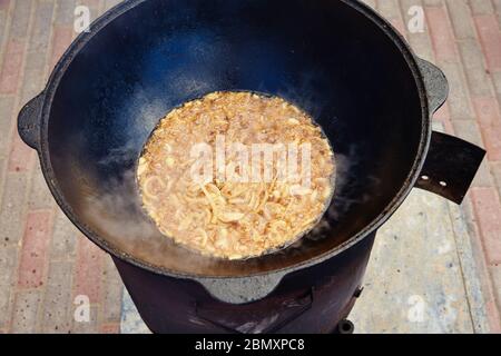 National Uzbek dish pilaf, pilaw, plov, rice with meat in big pan. Cooking process, open fire. Cooking in a cauldron on fire. .Preparation stages Stock Photo