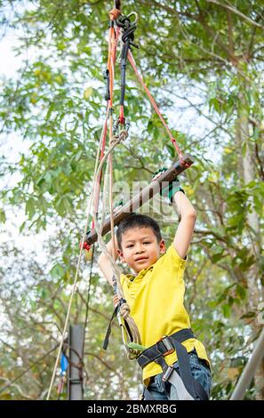 Asean boy hanging rod Tied with ropes and slings background blurry tree. Stock Photo