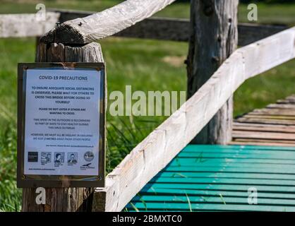 Aberlady nature reserve, East Lothian, Scotland, United Kingdom. 11th May, 2020. UK Weather: Quiet at the reserve during the Covid-19 lockdown. A notice on the narrow wooden pedestrian footbridge urges people to take turns crossing in order to maintain social distancing Stock Photo