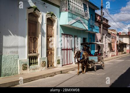 Horse drawn carriage acting as public transport driving through a quiet neighbourhood in Santa Clara, Cuba Stock Photo