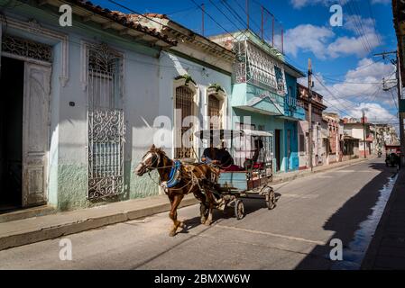 Horse drawn carriage acting as public transport driving through a quiet neighbourhood in Santa Clara, Cuba Stock Photo