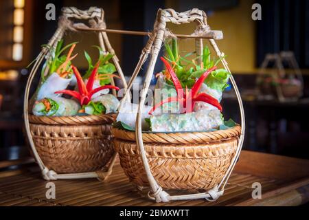 Vietnamese food served in traditional wicker baskets in a restaurant in Hoi An Stock Photo