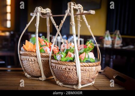 Vietnamese food served in traditional wicker baskets in a restaurant in Hoi An Stock Photo