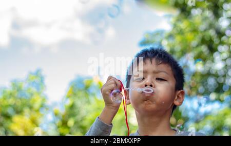 Portrait asia boy blowing bubbles  in garden. Stock Photo