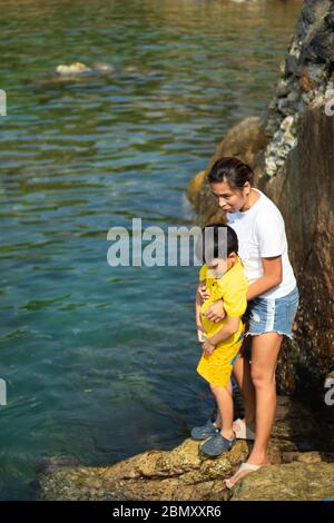 Mother and son watching the fish in the sea. Stock Photo