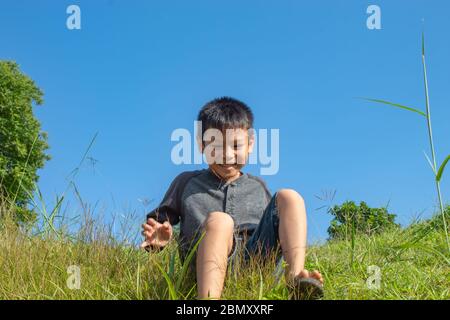 Asian boy Sit on the grass hill mountain Stock Photo