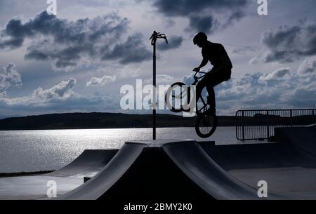 A young boy performs a trick at Largs Skate park. Stock Photo