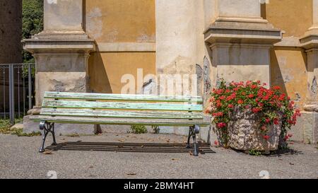 Weathered bench with flowers in front of church in a small village on Corsica Stock Photo