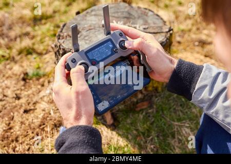 Close up mans hands holding a drones remote controller. A aerial shoot of a bridge is on the screen of smartphone. Real footage concept. Liberec Stock Photo