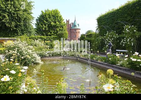 Traditional formal public garden, in bloom in the summer with a lake & small fountains in the foreground, located near Kvaerndrup, in the south of the Stock Photo