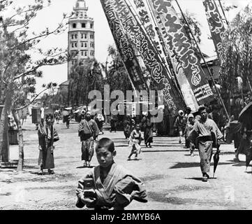 [ 1890s Japan - Japan’s First Skyscraper ] —   Theater Street in Asakusa, Tokyo. The huge banners promote the theaters.  In the background Ryounkaku (凌雲閣) can be seen. It was Japan’s very first skyscraper, better known as Asakusa Junikai (浅草十二階, Asakusa Twelve Stories).  It housed Japan's first electric elevator.   Ryounkaku was destroyed by the Great Kanto Earthquake (Kanto Daishinsai) of September 1, 1923 (Taisho 12).  19th century vintage glass slide. Stock Photo