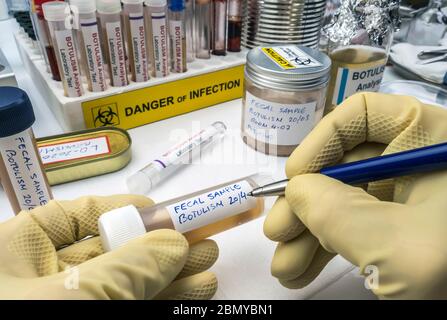 Specialized scientist writes on label of fecal sample, botulism infection in sick people, conceptual image Stock Photo