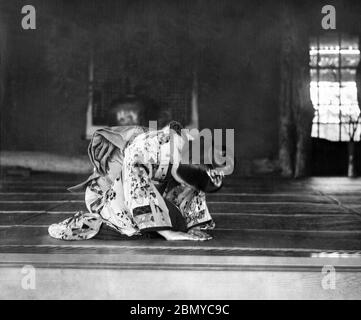 [ 1890s Japan - Japanese Way of Receiving a Guest ] —   Receiving a guest. A woman in kimono bows deeply while being seated on tatami (rice mats) in a traditional Japanese room.  From a series of glass slides published (but not photographed) by Scottish photographer George Washington Wilson (1823–1893). Wilson’s firm was one of the largest publishers of photographic prints in the world.  19th century vintage glass slide. Stock Photo