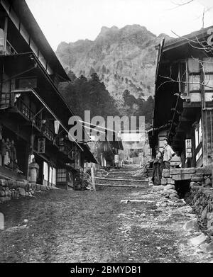 [ 1890s Japan - Japanese Mountain Town ] —   A rare view of Japanese inns along the road to Myogi Shrine (妙義神社) in Tomioka (富岡市), Gunma Prefecture. In the background Mount Myogi (妙義山) can be seen. The area was near the Nakasendo, one of the two routes that connected Edo (modern-day Tokyo) to Kyoto.  Mt. Myogi is one of the Three Great Places of Rugged Beauty in Japan (日本三大奇勝, Nihon Sandai Kisho). The other two are Yabakei Gorge (耶馬溪) in Kyushu and Kankakei Gorge (寒霞渓) in Shikoku.  From a series of glass slides published (but not photographed) by Scottish photographer George Washington Wilson ( Stock Photo